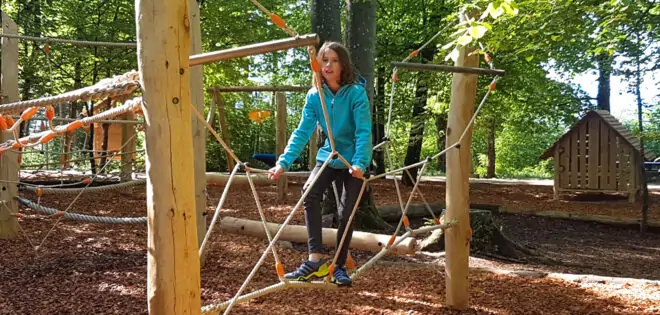 Mädchen auf Klettergerüst auf einem Waldspielplatz